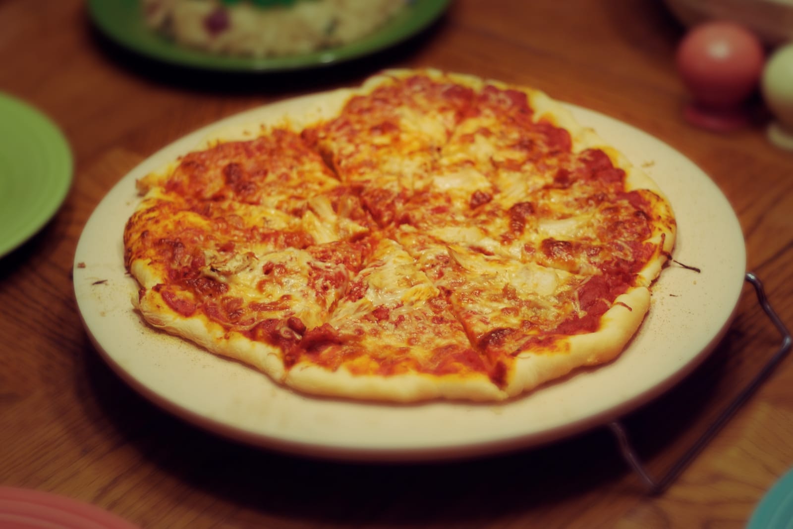 Færdigbagt pizza med sprød, gennembagt bund liggende på en rund lys bagesten af keramik