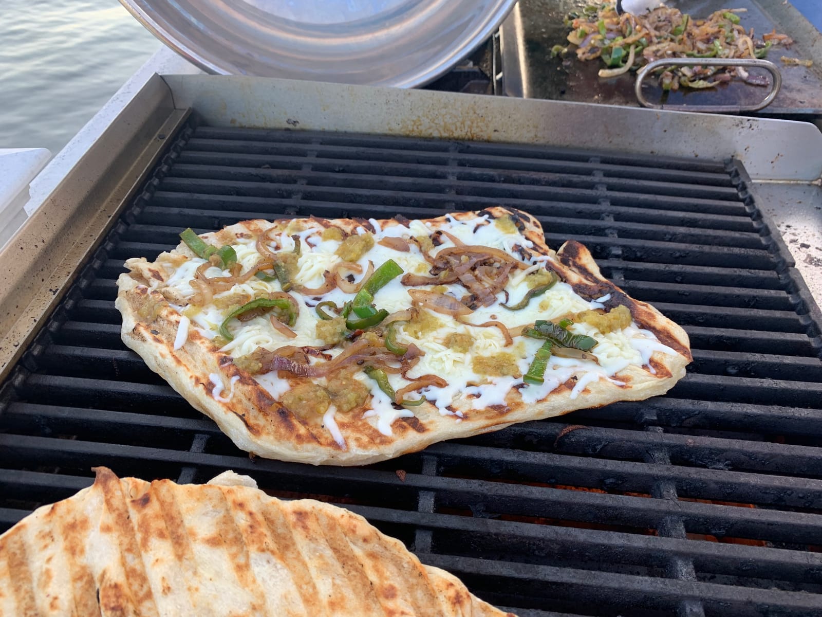 Pizza med bobler og grillstriber bager direkte på risten i en gasgrill udendørs